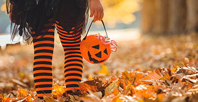 Young girl dressed for Halloween with a pumpkin filled with candy. 